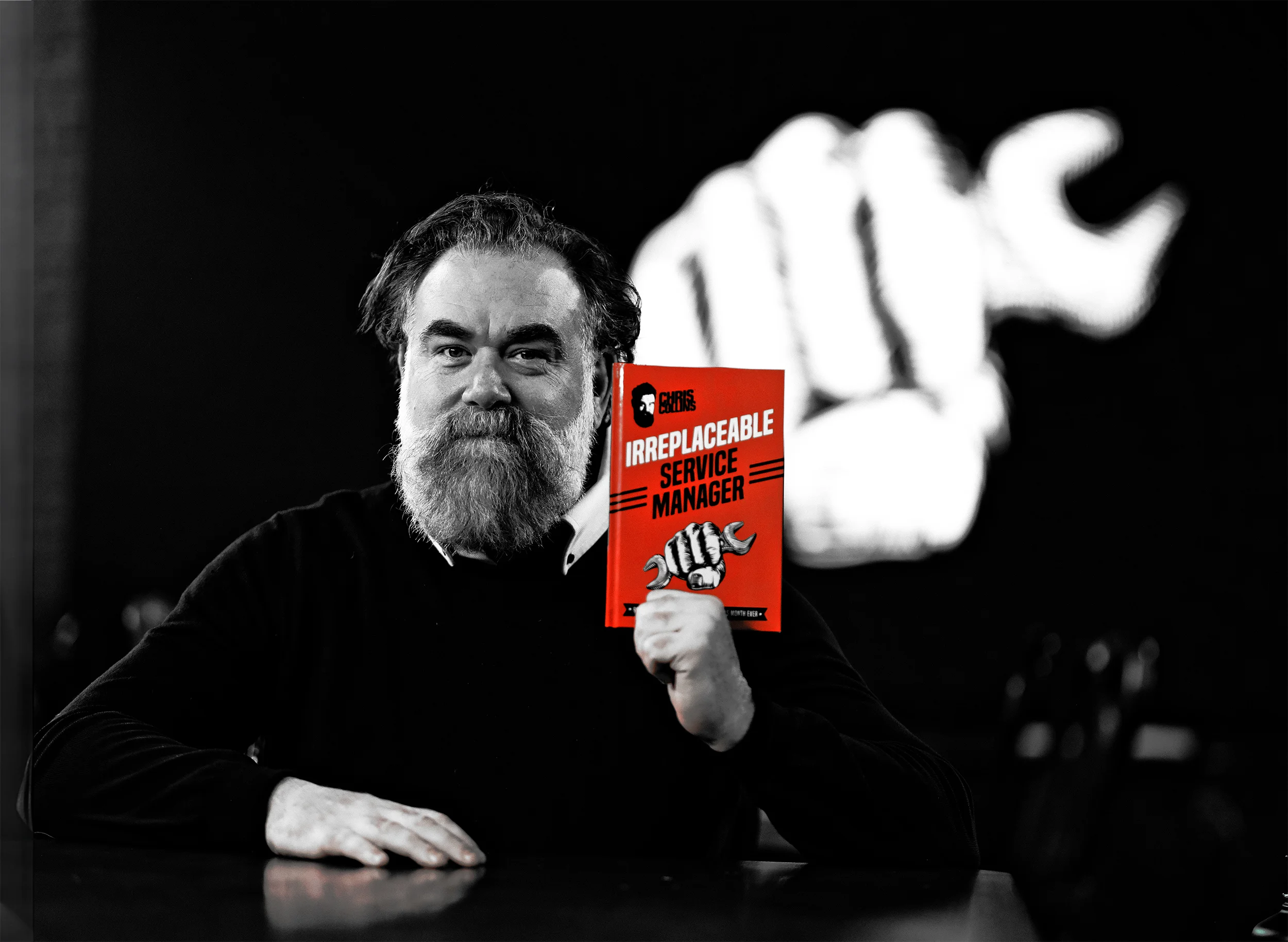 Person holding an “Irreplaceable Service Manager” book with Chris Collins branding in front of a fist graphic